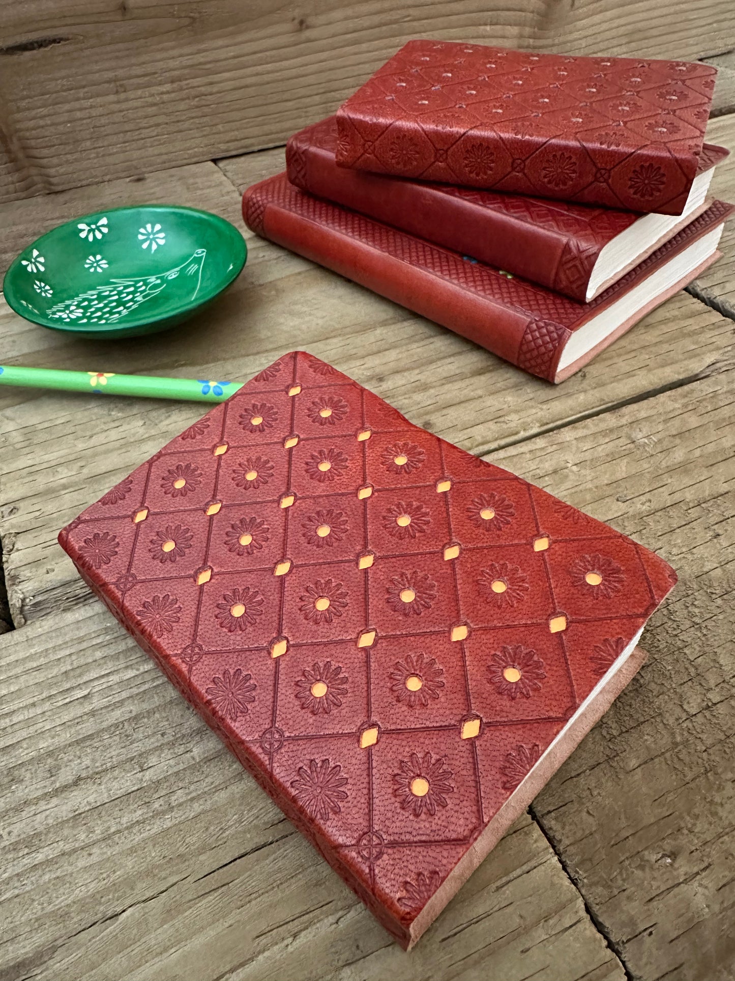 Orange mini leather notebook showing embossed leather craftsmanship and decorative detailing
