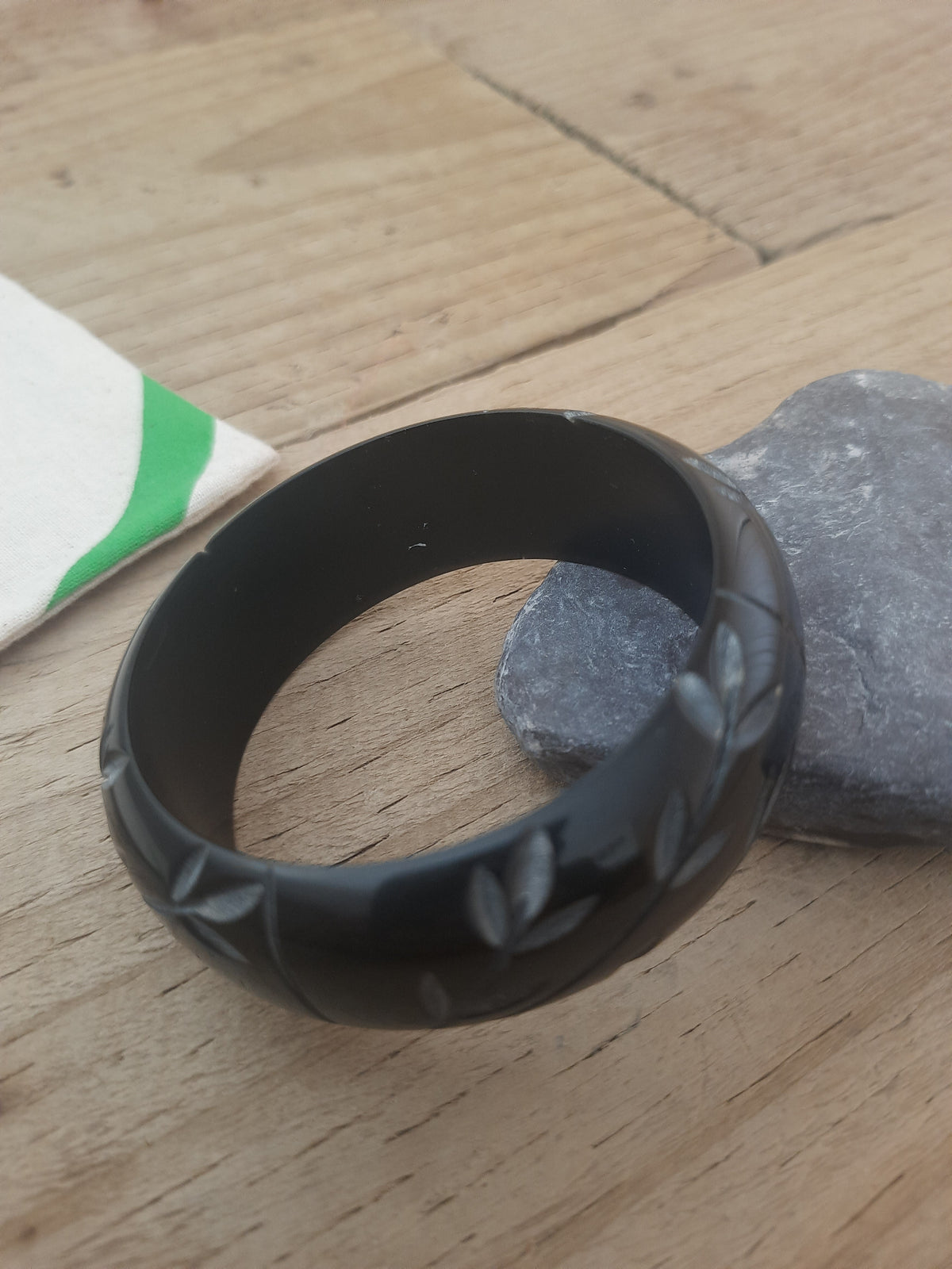 Black floral bangle showing its tactile engraved design