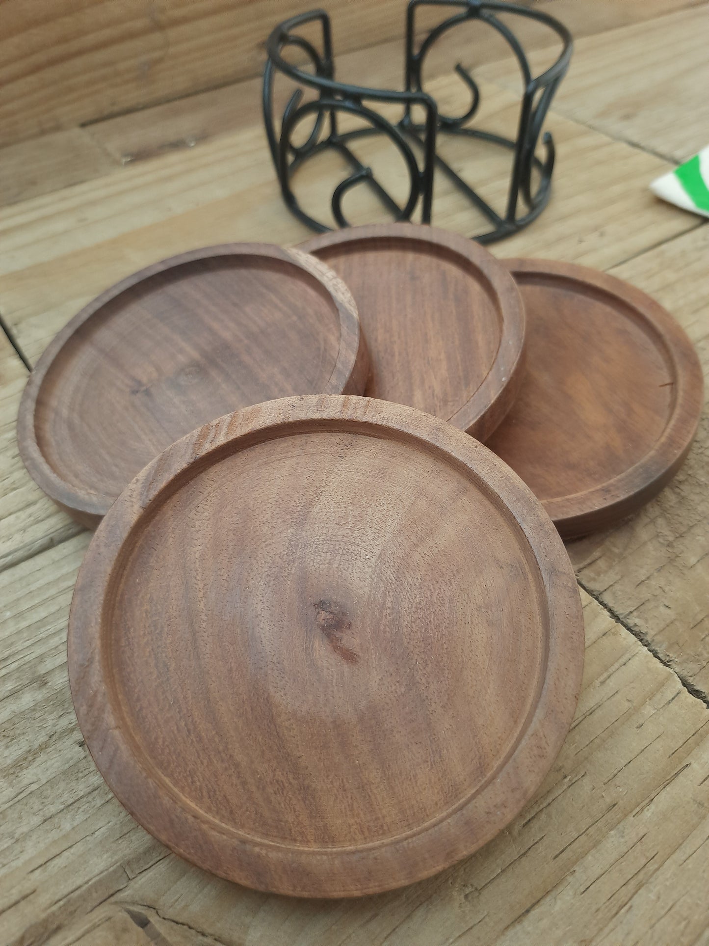 Set of four round mango wood coasters with black metal holder