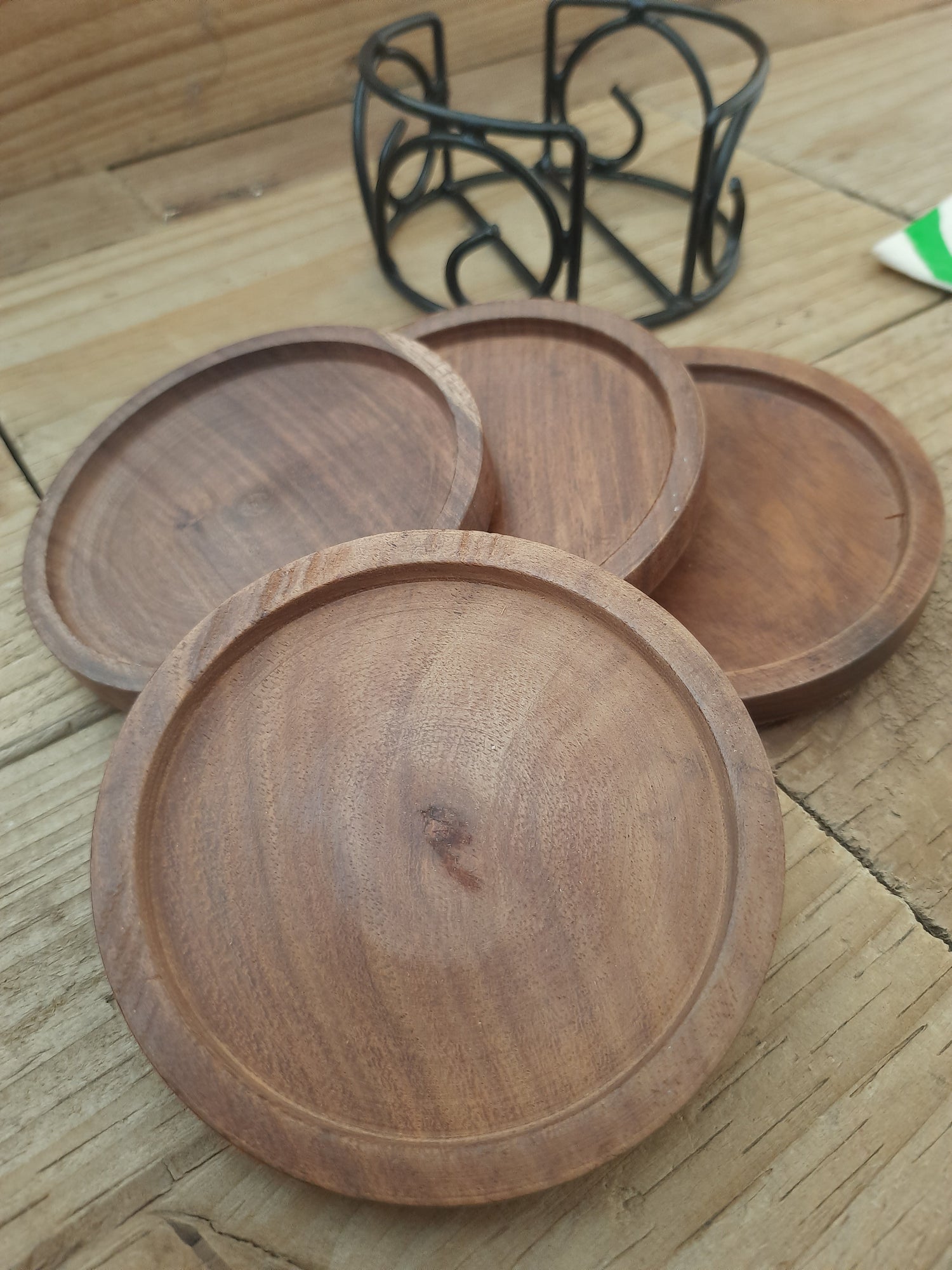 Set of four round mango wood coasters with black metal holder